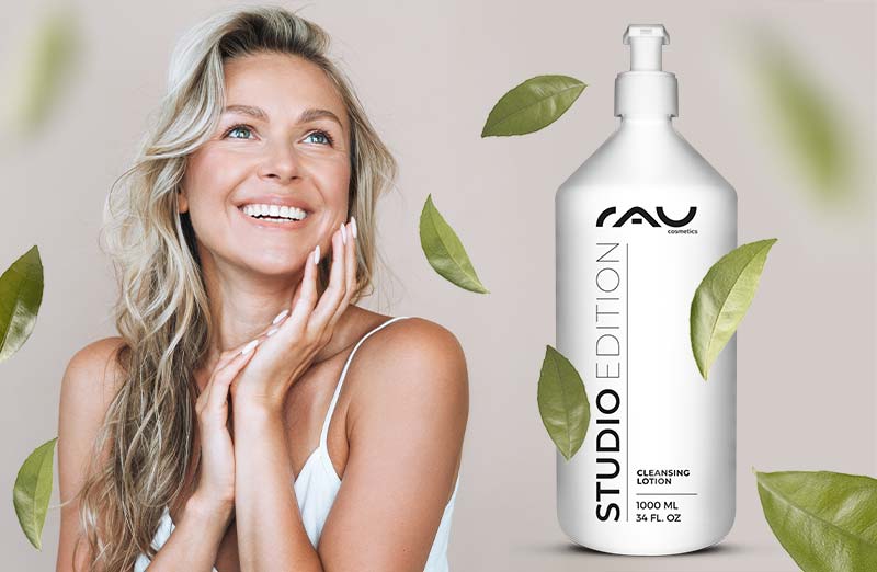 Frau mit glänzendem Lächeln, hält die RAU Cosmetics STUDIO EDITION Reinigungslotion in weißem Flakon.